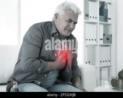 Älterer Mann mit Herzinfarkt auf dem Sofa Stockfoto