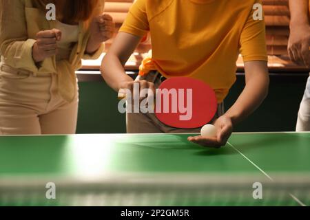 Eine Frau, die Tischtennis mit Freunden drinnen spielt, Nahaufnahme Stockfoto