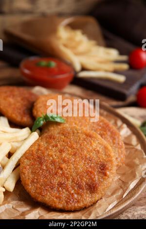 Köstliche gebratene panierte Schnitzel, serviert auf einem Holztisch, Nahaufnahme Stockfoto