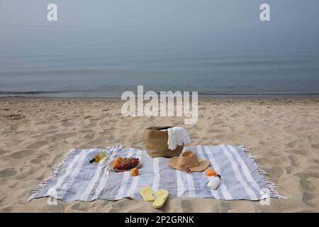 Tasche, Decke, Wein und andere Sachen für ein Strandpicknick am Sandstrand Stockfoto