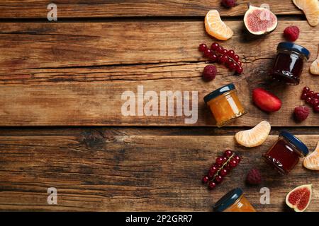 Gläser mit verschiedenen Marmeladen und frischen Zutaten auf Holztisch, flach liegend. Platz für Text Stockfoto