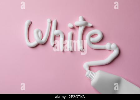 Word White mit Zahnpasta und Tube auf pinkfarbenem Hintergrund, Draufsicht Stockfoto