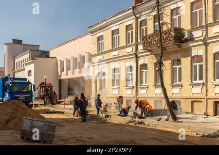 Grodno, Weißrussland - 06. März 2022: Arbeiter mit Hilfe von Erdbewegungsmaschinen bauen unterirdische Versorgungseinrichtungen in einer der ältesten Straßen wieder auf Stockfoto