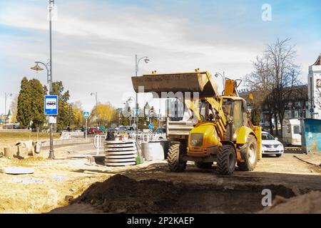 Grodno, Weißrussland - 06. März 2022: Arbeiter mit Hilfe von Erdbewegungsmaschinen bauen unterirdische Versorgungseinrichtungen in einer der ältesten Straßen wieder auf Stockfoto