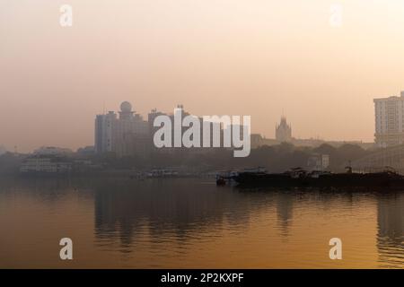 Blick auf das New Secretariat Building und den Calcutta High Court in raucher Atmosphäre über dem Hooghly River in Kalkutta, der Hauptstadt von Westbengalen, Indien Stockfoto