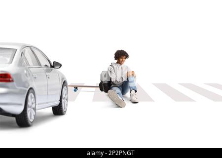 Auto an einem Fußgängerübergang und ein afroamerikanischer Typ mit einem Skateboard, der mit einem verletzten Bein auf weißem Hintergrund sitzt Stockfoto