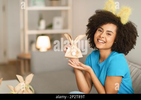 Fröhliche Junge Schwarze Frau, Die Zu Hause Handgemachte Ostergeschenke Macht Stockfoto