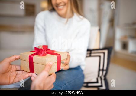 Der Millennial-araber schenkt einer europäischen Frau eine Box mit Geschenk, gratuliert zum Valentinstag Stockfoto