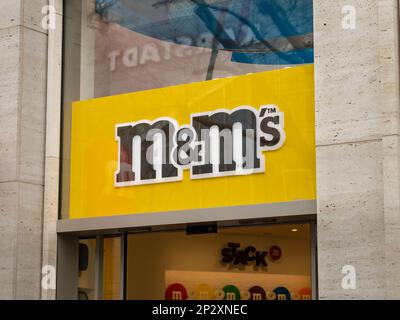 Das Logo von M&M auf der Fassade des Ladengebäudes. Marke des Unternehmens Mars Inc. Ein Geschäft in der Stadt für Menschen, die Schokolade und Süßigkeiten lieben. Stockfoto