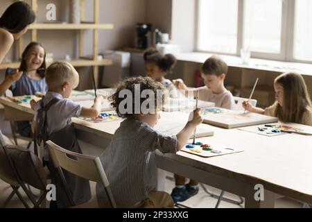 Eine Gruppe kleiner künstlerischer Schüler, die in Acrylfarben zeichnen Stockfoto