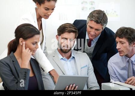 Fachkundige Finanzplaner bei der Arbeit. Eine Gruppe von Geschäftsleuten, die sich etwas auf einem digitalen Tablet ansehen. Stockfoto