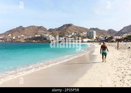 Männer, die an einem perfekten Sommertag auf der Insel Sao Vicente, Cabo verde, auf einem wunderschönen weißen Sandstrand von Laginha im Stadtzentrum von Mindelo spazieren Stockfoto
