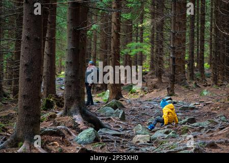 Das Kind rutschte aus und fiel auf den geneigten, nassen Boden. Polnische Berge Stockfoto