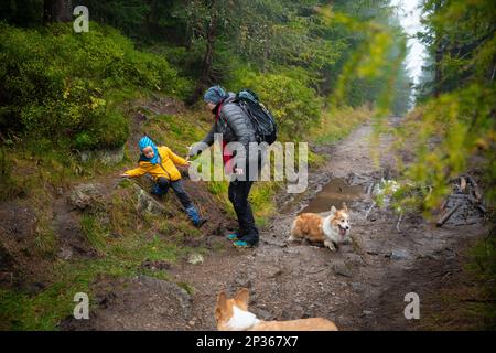 Das Kind rutschte aus und fiel auf den geneigten, nassen Boden. Polnische Berge Stockfoto