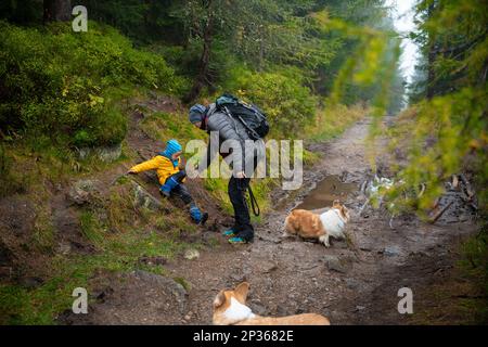 Das Kind rutschte aus und fiel auf den geneigten, nassen Boden. Polnische Berge Stockfoto
