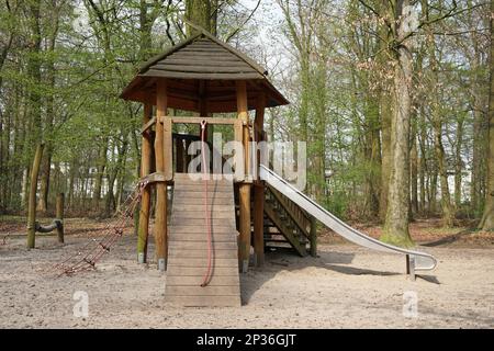 Spielplatz im Wald mit Holzhütte, Klettergerät und Rutsche Stockfoto