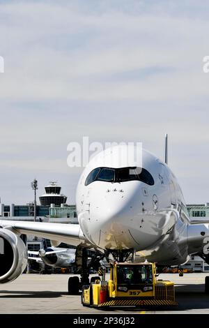 Lufthansa Airbus A350-900 Abschleppen mit Rückstoßwagen vor Terminal 2 mit Turm, Flughafen München, Oberbayern, Bayern, Deutschland Stockfoto