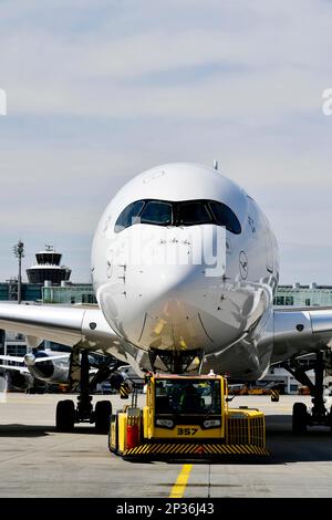 Lufthansa Airbus A350-900 Abschleppen mit Rückstoßwagen vor Terminal 2 mit Turm, Flughafen München, Oberbayern, Bayern, Deutschland Stockfoto