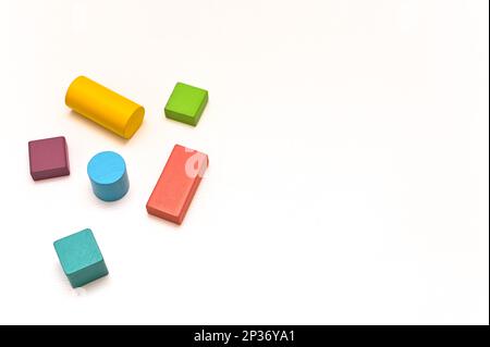 Mehrfarbige Holzfiguren unterschiedlicher geometrischer Formen. Entwicklung des Montessori-Konstruktors für Kinder. Auf weißem Hintergrund. Konzept. Schriftzeichen Stockfoto