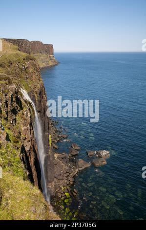 Blick auf die Küste mit einem Wasserfall, der über Klippen ins Meer stürzt, mit Kilt Rock im Hintergrund, Mealt Falls, in der Nähe von Sound of Raasay Stockfoto