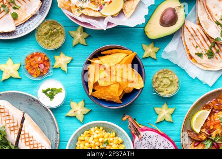 Gemischter Mix aus traditioneller mexikanischer Küche. Tisch mit verschiedenen mexikanischen Gerichten. Käsenachos, Tacos, Guacamole, Quesadilla, Burrito, Fajitas, Tortilla Stockfoto