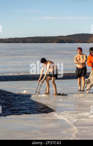 Das jährliche Winterfestival in Ludvika Schweden lockt die Menschen an, ein Bad bei 2 Grad Celsius zu nehmen, aber die Sonne scheint. Stockfoto