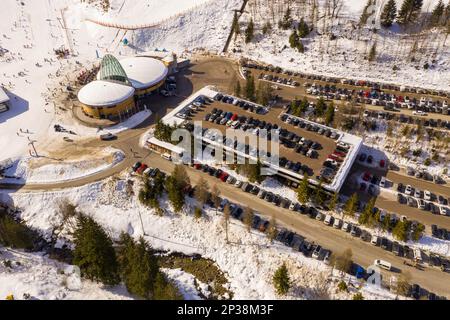 Drohnenfotografie von Skigebiet, Parkplatz, Bergen und Wald am sonnigen Wintertag Stockfoto