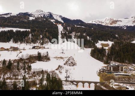 Drohnenfotografie des Berghimmelsabhangs, Eisenbahnbrücke über den Abhang und Himmelsaufzüge an bewölkten Wintertagen Stockfoto