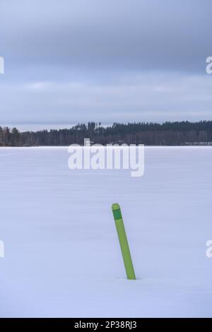 Grüne Spar-Boje auf einem gefrorenen See in Hollola, Finnland Stockfoto