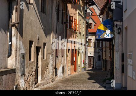 Stadt Skofja Loka in Slowenien, alte Häuser entlang einer engen Kopfsteinpflasterstraße in der Altstadt. Stockfoto