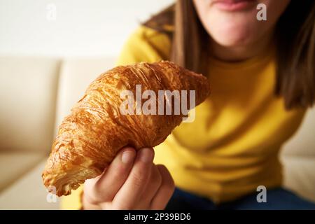 Teenager-Mädchen, die Croissants zum Frühstück isst, aus der Nähe Stockfoto