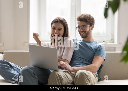 Ein fröhliches Paar, das sich auf einem Laptop per Videogespräch verliebte Stockfoto