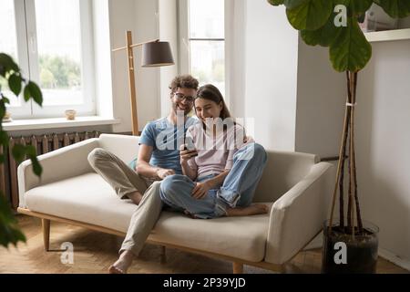 Aufgeregtes, fröhliches junges Paar, das sich per Videoanruf mit dem Smartphone unterhält Stockfoto