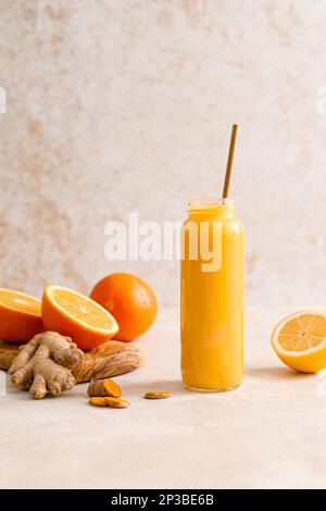 Smoothie. Gesunder, frischer, roher Detox-Citrus-Smoothie mit Orange, Zitrone, Ingwer und Kurkuma in einer Glasflasche auf einem Tisch. Gesunde Ernährung vegane Lebensmittel voll Stockfoto