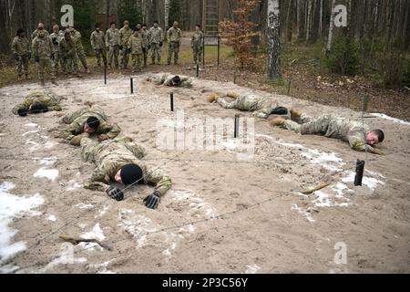 USA Soldaten mit 207. Brigaden des militärischen Nachrichtendienstes manövrieren während der jährlichen Übung der Brigade Lightning Focus im Trainingsbereich Grafenwoehr des 7. Armeeausbildungskommandos, Deutschland, 25. Januar 2023 durch das Low Crawl hindurch. Lightning Focus 2023 bietet die Möglichkeit, die Fähigkeiten von Einzelpersonen und Mannschaften im Waffengeschäft zu verbessern, Schulungen zu grundlegenden Fähigkeiten von Soldaten, Entwicklung von Juniorsoldaten und NCO zu absolvieren, den Zusammenhalt von Einheiten und den Aufbau von Teams zu verbessern und auf Szenarien basierende Schulungen zur Unterstützung operativer Intelligenz zur Zertifizierung von Intelligence-Plattformen zu absolvieren; Vorbereitung zur Unterstützung von SETAF-AF, USAREUR-AF und den USA Stockfoto
