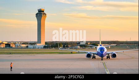 Austin, Texas - Februar 2023: Boeing 737 Passagierjet trifft am Flughafen der Stadt ein. Der Flugverkehrskontrollturm des Flughafens befindet sich im Hintergrund. Stockfoto