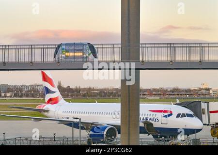 London, England, Vereinigtes Königreich - Januar 2023: British Airways Airbus A320 Jet (Registrierung G-TTNE) am Terminal 5 des Flughafens Heathrow mit einem Zug zum Abstellen von Parkplätzen Stockfoto