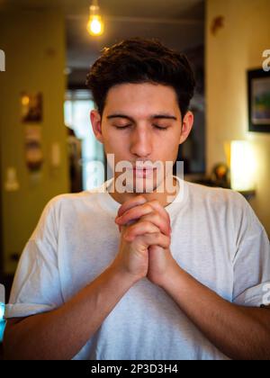 Ein junger Mann, der mit den Händen flehte, betete Stockfoto