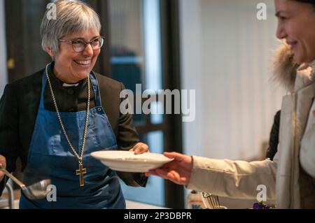 Coburg, Deutschland. 05. März 2023. Der regionale Bischof Dorothea Greiner (r) serviert bei der Eröffnung einer Vesperkirche im Kirchenhaus von St. Moriz Speisen. Die Vesperkirche bietet Mittagessen, kulturelle Veranstaltungen und andere Aktivitäten für zwei Wochen. Kredit: Pia Bayer/dpa/Alamy Live News Stockfoto