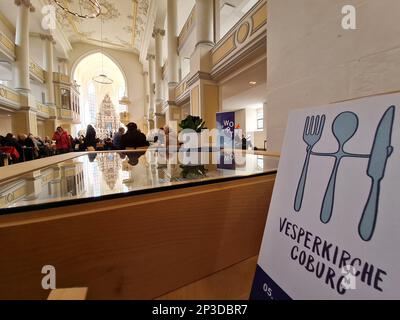 Coburg, Deutschland. 05. März 2023. Ein Schild mit der Aufschrift „Vesperkirche Coburg“ steht an einer Wand an der Öffnung der Vesperkirche im Kirchenzimmer von St. Moriz. Die Vesperkirche bietet Mittagessen, kulturelle Veranstaltungen und andere Aktivitäten für zwei Wochen. Kredit: Pia Bayer/dpa/Alamy Live News Stockfoto