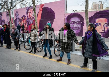 Madrid, Spanien. 05. März 2023. Frauen, die vor einem feministischen Wandbild stehen, werden während einer menschlichen Kette gesehen, um Gewalt gegen Frauen anzuprangern und den feministischen Kampf als Teil der Aktivitäten zum Internationalen Frauentag sichtbar zu machen. In dem Wandgemälde erscheinen die Gesichter von 15 Frauen, die Teil der Geschichte für ihren Kampf für Gleichheit sind, wie Angela Davis, Frida Kahlo, Nina Simone und andere. Kredit: Marcos del Mazo/Alamy Live News Stockfoto