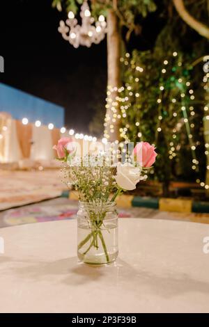 Ein farbenfroher Strauß frisch geschnittener Blumen in einer transparenten Glasvase auf einem Tisch Stockfoto