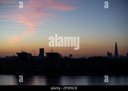 Rosa Cirrostratuswolken über der Themse und dem Südosten Londons. Die Gebäude sind vom Himmel des Sonnenuntergangs abgeschirmt. Stockfoto