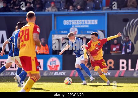 Rostock, Deutschland. 05. März 2023. Fußball: 2. Bundesliga, Hansa Rostock - Karlsruher SC, Matchday 23, Ostseestadion. Kevin Schumacher von Rostock (Mitte) und Paul Nebel von Karlsruhe (rechts) kämpfen um den Ball. Kredit: Gregor Fischer/dpa - WICHTIGER HINWEIS: Gemäß den Anforderungen der DFL Deutsche Fußball Liga und des DFB Deutscher Fußball-Bund ist es verboten, im Stadion aufgenommene Fotos und/oder das Spiel in Form von Sequenzbildern und/oder videoähnlichen Fotoserien zu verwenden oder verwenden zu lassen./dpa/Alamy Live News Stockfoto