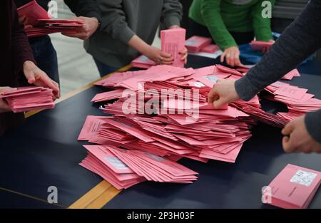 05. März 2023, Hessen, Frankfurt/Main: Wahlhelfer sortieren Umschläge für abwesende Wahlurnen auf einem Tisch in einer Ausstellungshalle. Etwa 509.000 Einwohner Frankfurts werden aufgefordert, für einen neuen Stadtführer zu stimmen. Foto: Arne Dedert/dpa Stockfoto