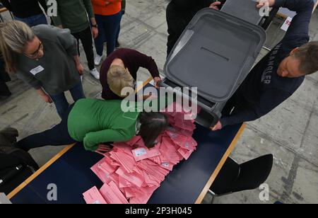 05. März 2023, Hessen, Frankfurt/Main: Wahlhelfer geben an einem Tisch in einer Ausstellungshalle mit abwesenden Wahlzetteln für die Bürgermeisterwahl einen Tipp aus. Etwa 509.000 Einwohner Frankfurts werden aufgefordert, für einen neuen Stadtführer zu stimmen. Foto: Arne Dedert/dpa Stockfoto