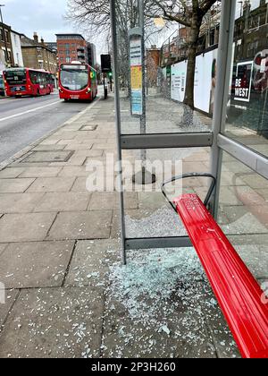 Ein verwundeter Busbunker in Acton Town London. Zerbrochenes Glas liegt auf dem Bürgersteig, als zwei Glasscheiben zertrümmert wurden. Stockfoto