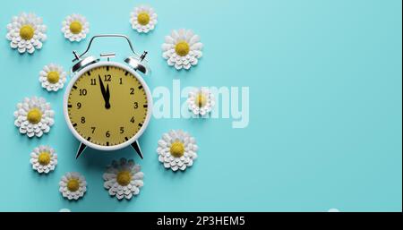 Wecker umgeben von Blumen. Übergangszeit Sommerzeit, Sommerzeit. Stockfoto