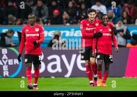 05. März 2023, Nordrhein-Westfalen, Leverkusen: Fußball: Bundesliga, Bayer Leverkusen - Hertha BSC, Spieltag 23, BayArena. Leverkusens Sardar Azmoun (Mitte) und der Torschütze Jeremie Frimpong (rechts) feiern nach dem Tor von 2:0. Leverkusen's Moussa Diaby auf der linken Seite. Foto: Marius Becker/dpa - WICHTIGER HINWEIS: Gemäß den Anforderungen der DFL Deutsche Fußball Liga und des DFB Deutscher Fußball-Bund ist es verboten, im Stadion aufgenommene Fotografien und/oder das Spiel in Form von Sequenzbildern und/oder videoähnlichen Fotoserien zu verwenden oder verwenden zu lassen. Stockfoto