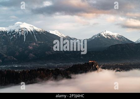 2022 12 30, Bled, Slowenien: Schloss Bled mit Blick über den Bleder See, bedeckt von Nebel, mit den Julischen Alpen im Hintergrund Stockfoto